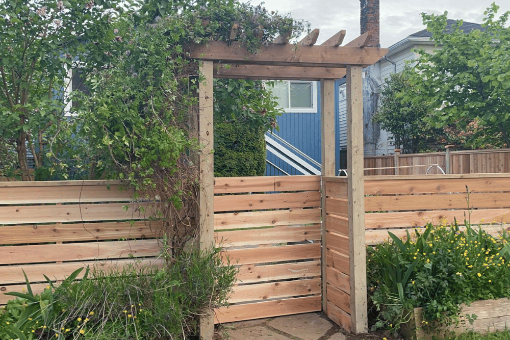 Fence contractors in Abbotsford built this custom cedar horizontal slat fence with a garden gate and pergola.